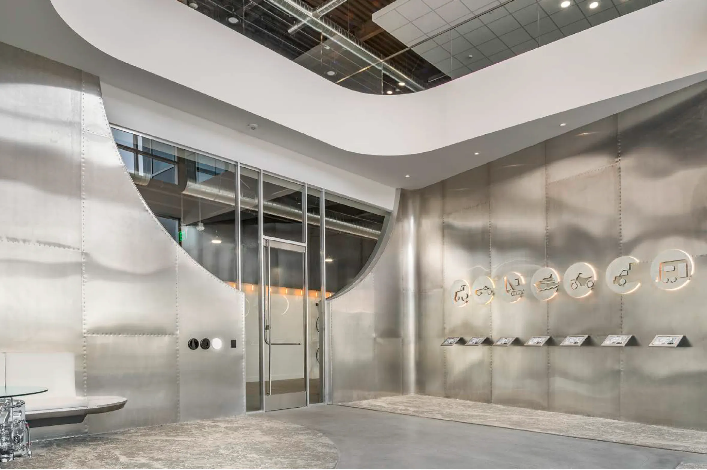 Lobby clad in riveted aluminum sheets with custom employee login stations below backlit laser-cut aluminum themes